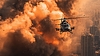 Helicóptero escapando de la explosión en la ciudad con fuego | Foto de stock