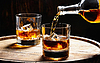 Gießt Whisky aus einer Flasche in ein Glas mit Eiswürfeln | Stock Foto